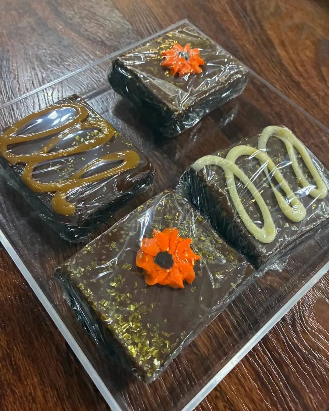 Four decorated brownies in a clear tray